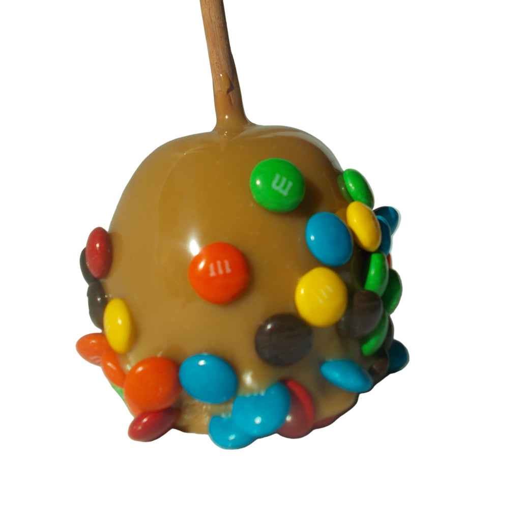 Caramel apple with colorful candy pieces on a stick against a white background