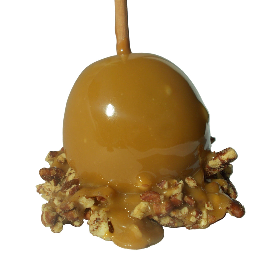 Caramel apple with nuts on a stick against a light background